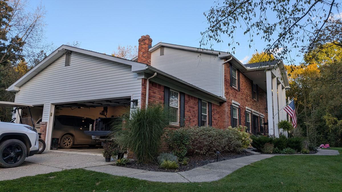 Front corner of the house: the brick front meets the white-sided garage wing