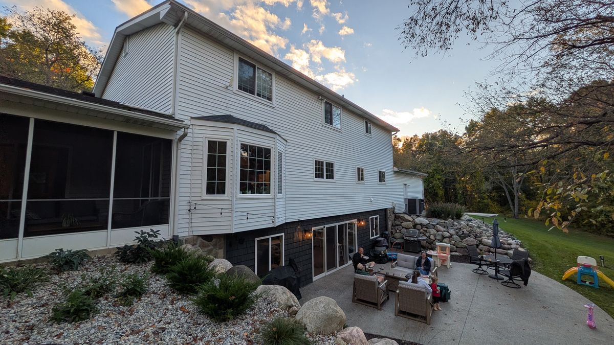 The back of the house from up the hill: the screened porch, the bay window, and the walkout patio between two boulder walls