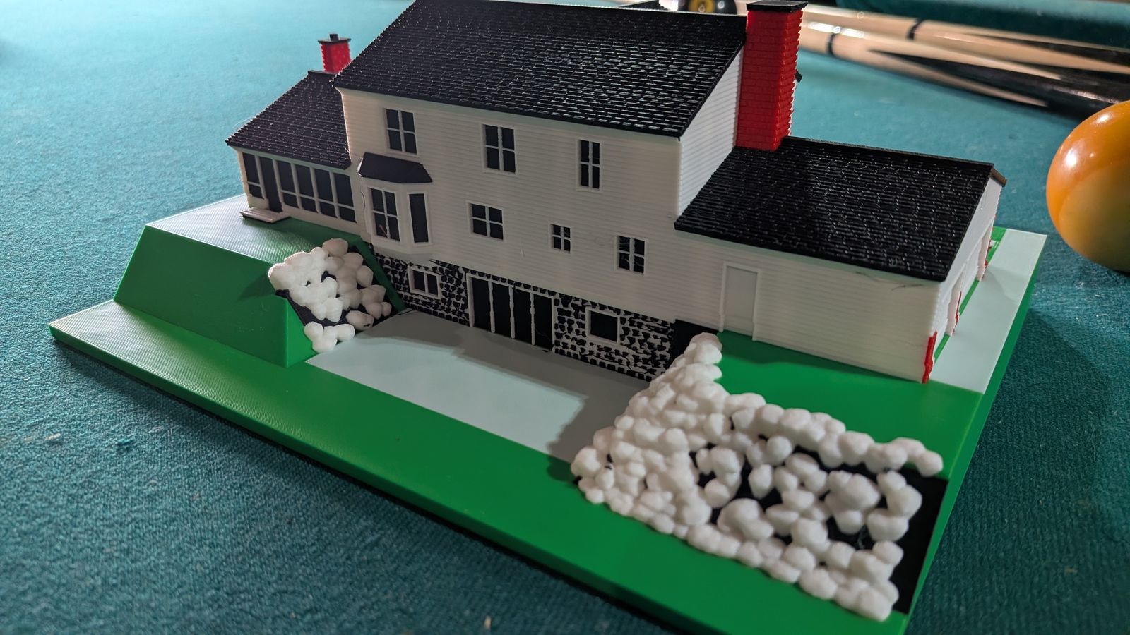 The back of the mini: white siding, the dark stone walkout level with sliding doors, the patio, and the boulder walls