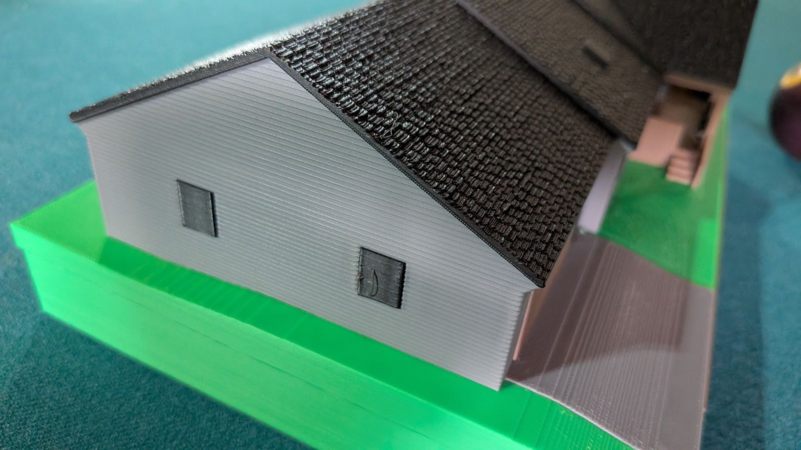 Close-up of the mini's garage end showing the two windows, siding lines, and textured shingles